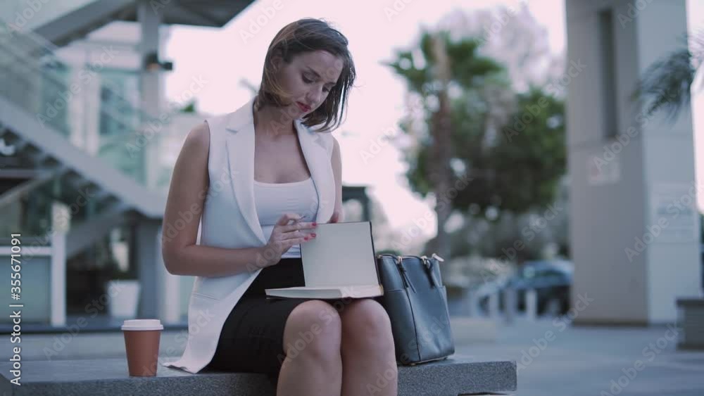 Fashionable entrepreneur having coffee break and writing notes in notepad Fashionable entrepreneur having coffee break and writing notes in notepad