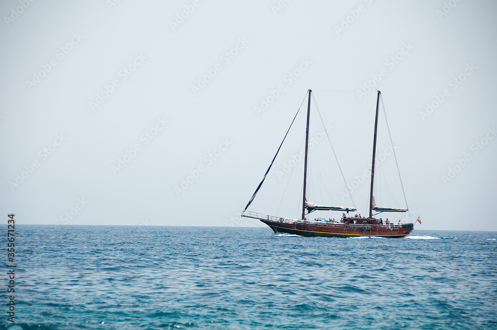 un velero rojo con las velas bajadas navegando por el mar azul