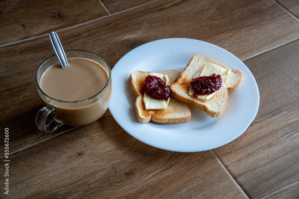 Cup of coffe with milk and two slices of toasted sandwich Bread with Butter and Raspberry Jam a white plate. Healthy breakfast with coffee. Top view. Free space for text.
