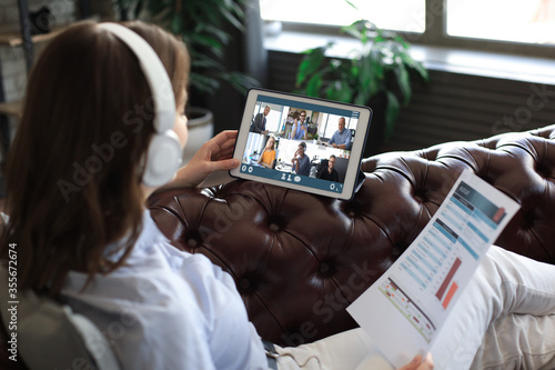Foto Business woman in headphones lying on sofa speak talking to her colleagues in video conference