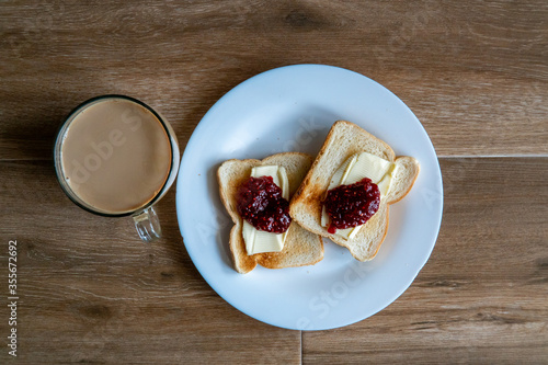 Obraz na płótnie Cup of coffe with milk and two slices of toasted sandwich Bread with Butter and Raspberry. Breakfast with coffee. Side view. Free space for text. w salonie
