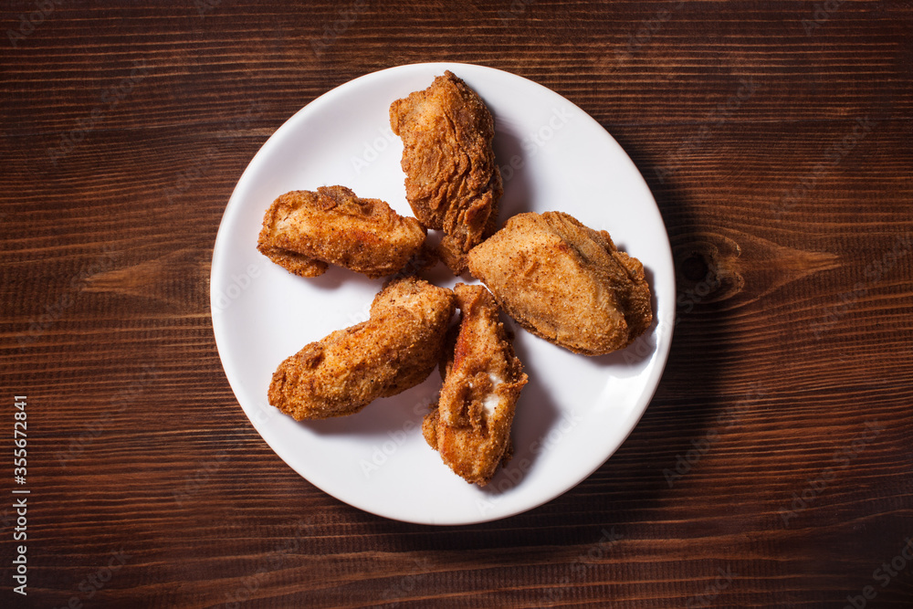 Fried chicken wings in batter on white plate over wooden background.. Spicy Deep Fried Breaded Chicken Wings with Ranch Fried chicken wings in batter on white plate over wooden background.. Spicy Deep Fried Breaded Chicken Wings with Ranch