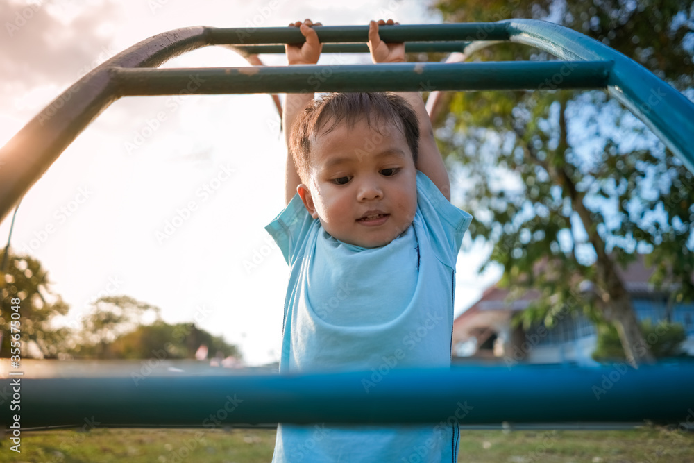 Cute little boy playing and hanging on ladder in kid playground Cute little boy playing and hanging on ladder in kid playground