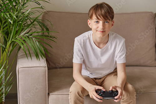 Young attractive guy sitting on a sofa holds a joystick.
