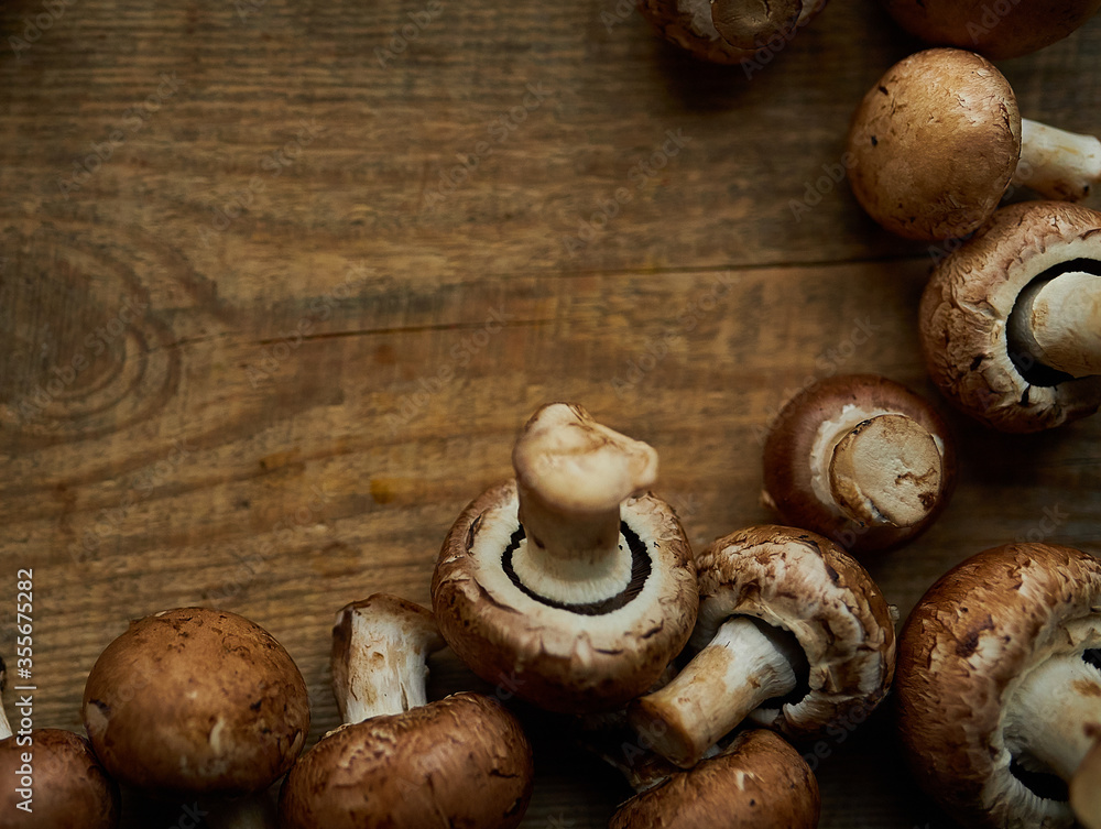 Frame of champignon mushrooms on a wooden background. Champignon mushrooms on a wooden board. Fresh healthy brown mushrooms.