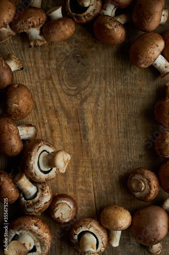 Frame of champignon mushrooms on a wooden background. Champignon mushrooms on a wooden board. Fresh healthy brown mushrooms.