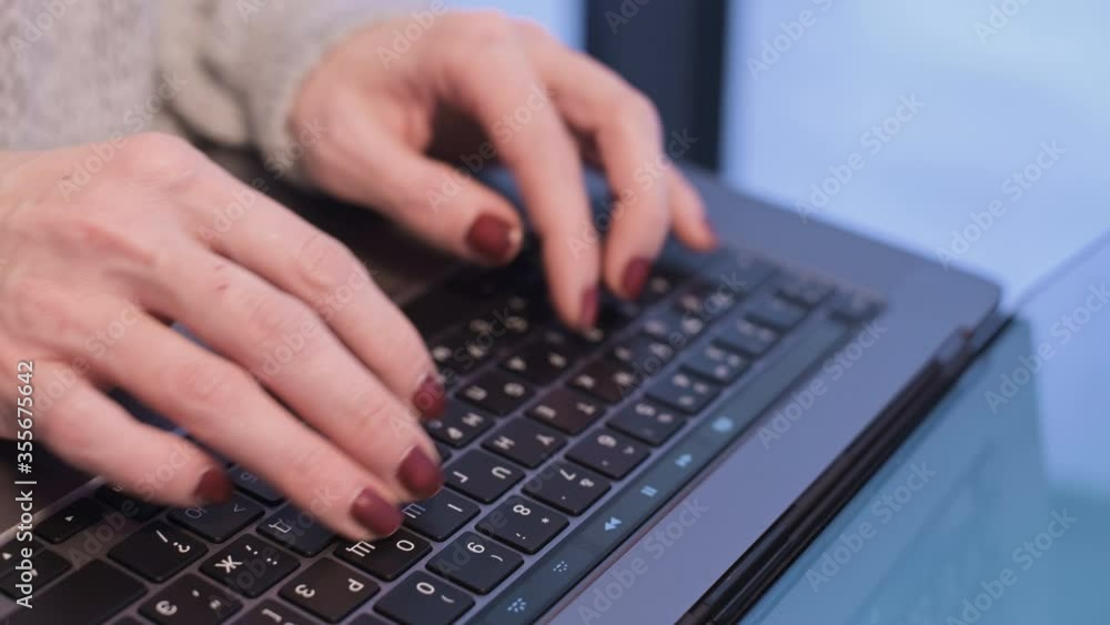 Close-up female hands typing on a laptop keyboard in the evening when the blue hour has already come outside the window. Shallow depth of field. winter forest in the background. Freelance concept Close-up female hands typing on a laptop keyboard in the evening when the blue hour has already come outside the window. Shallow depth of field. winter forest in the background. Freelance concept