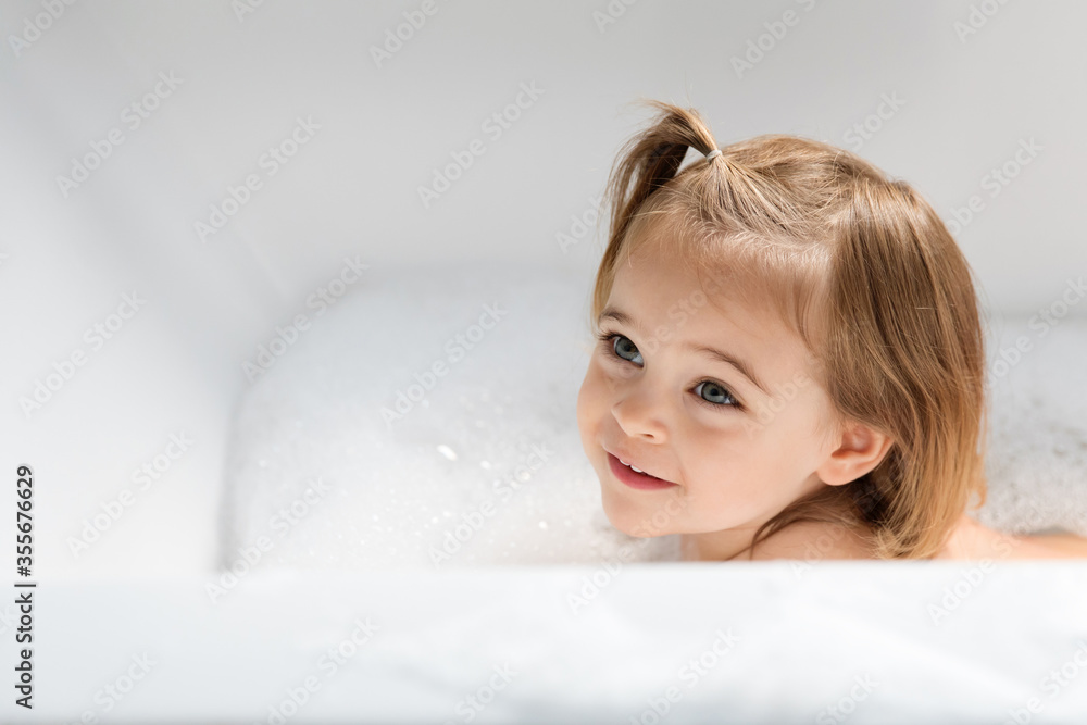 High angle view of smiling toddler girl looking away in bathtub at home High angle view of smiling toddler girl looking away in bathtub at home