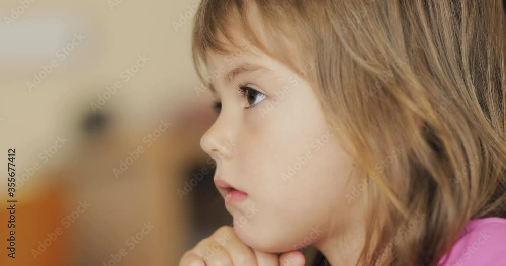 Adorable little girl in the sunlit living room watching tv and eating cereals Adorable little girl in the sunlit living room watching tv and eating cereals