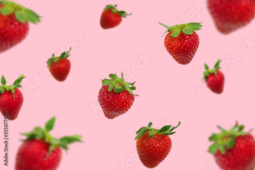 Colorful pattern of falling strawberries on pastel pink background