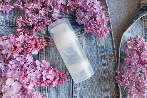 Mock up of transparent bottle of Intimate lubricant gel for branding and label and lilac flowers with trendy shadow top view. Denim background, Life style, floral flat lay.