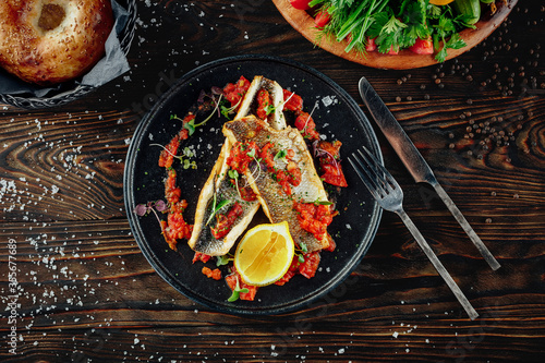 Two fillets of fish seabass with rich tomato and garlic sauce