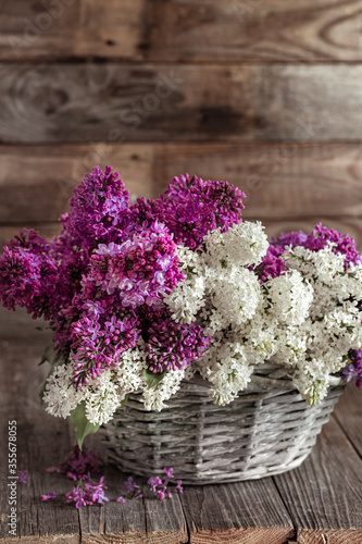 Spring composition lilac flowers in a basket on a wooden background.