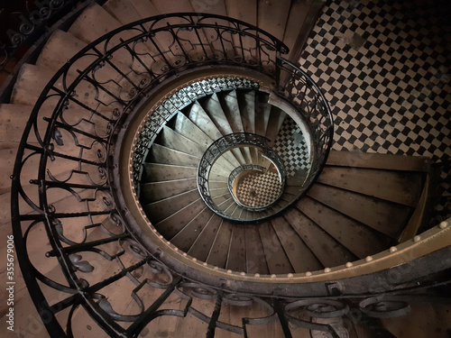 Vintage spiral staircase in an old European house. Top view  dark light.