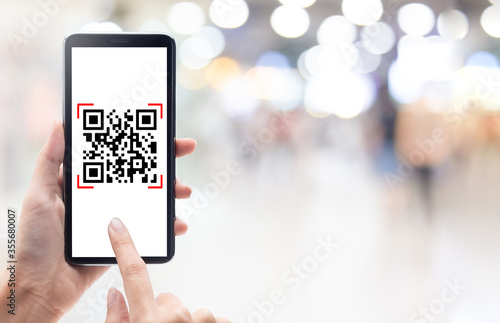 Hand using mobile smart phone scan Qr code on shopping mall background. Barcode reader, Qr code payment, Cashless technology, Digital money concept. photo