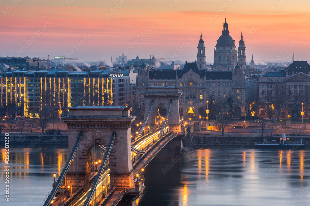 Naklejka premium Close up of St. Stephen's Basilica with Szechenyi Chain Bridge reflect in Danube river, Budapest during twilight