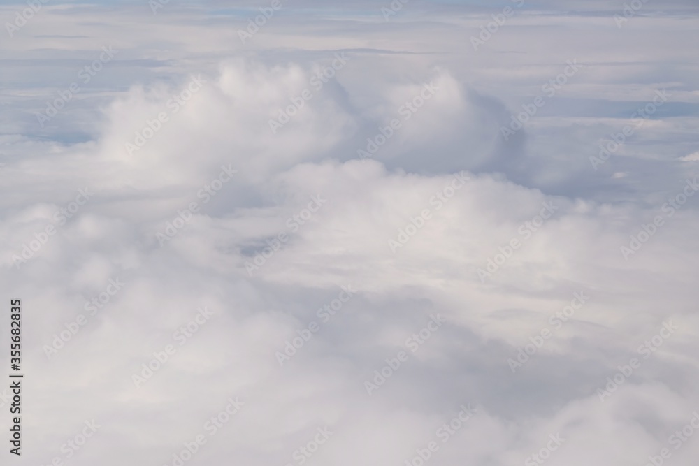 Fototapeta premium Beautiful white clouds backlit by the sun, view from the airplane window