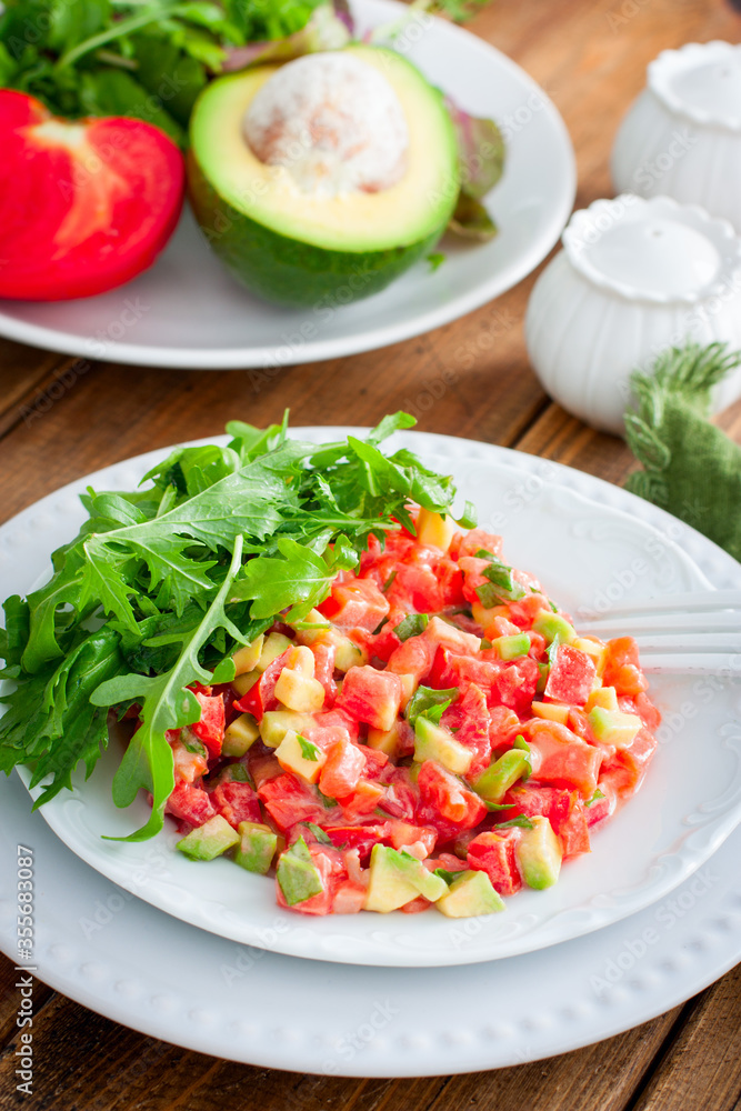 salad with avocado, tomato and red fish with arugula, selective focus