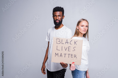 Fotografie Young african man and caucasian woman holding a cardboard poster with the message text BLACK LIVES MATTER isolated on white background