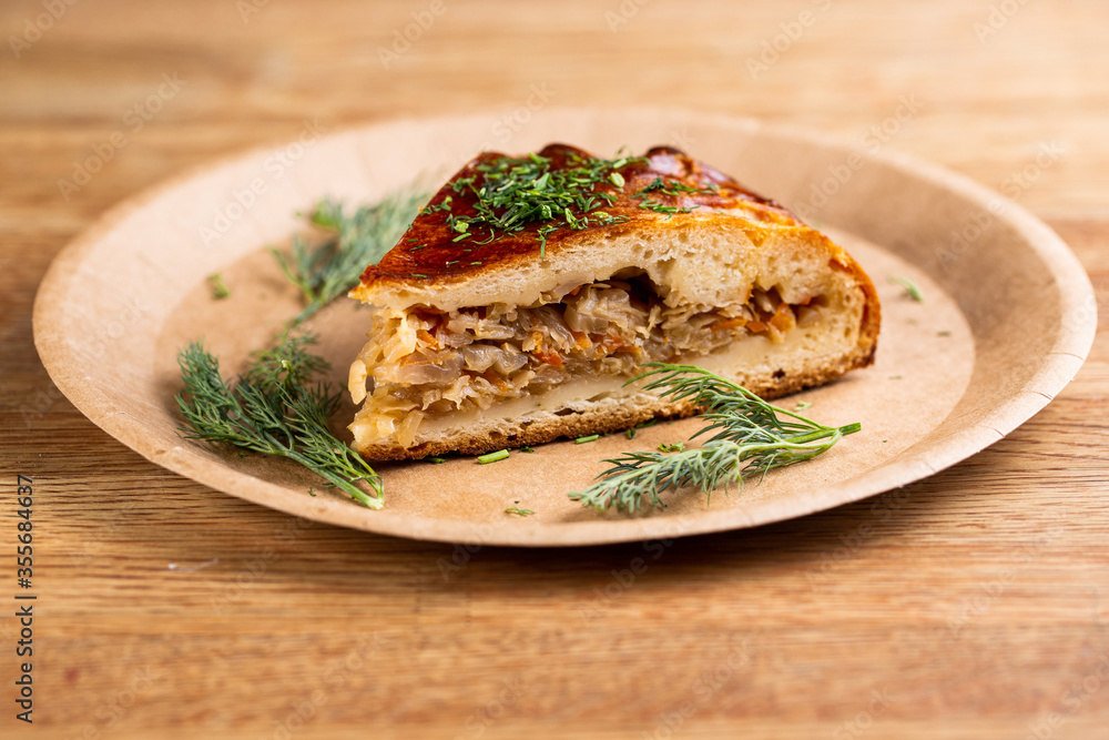 pie with stewed cabbage and carrots sprinkled with herbs on a disposable plate pie with stewed cabbage and carrots sprinkled with herbs on a disposable plate