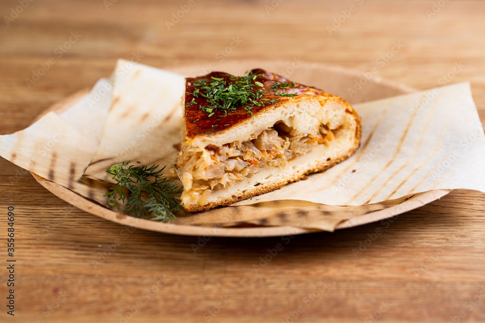 pie with stewed cabbage and carrots sprinkled with herbs on a disposable plate pie with stewed cabbage and carrots sprinkled with herbs on a disposable plate