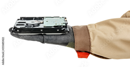 Computer hard drive lies in palm of man hand in black protective glove and brown uniform isolated on white background