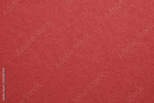 The surface of dark red cardboard. Rough paper texture with cellulose fibers. Saturated color. Background or wallpaper. Top view from above. Macro