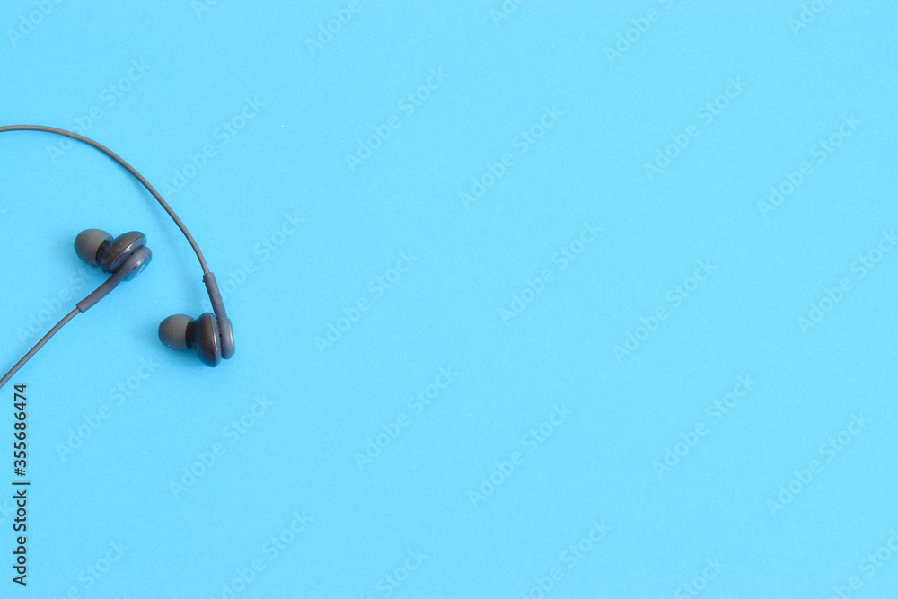 Black earbuds on light blue colorful monochrome background with copy space for text Black earbuds on light blue colorful monochrome background with copy space for text