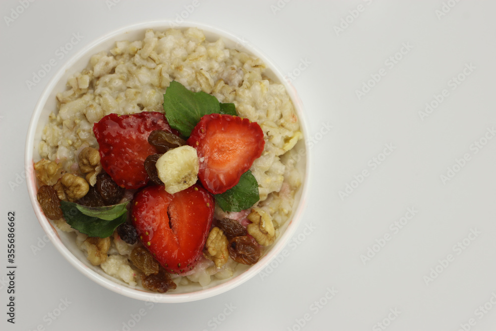 Bowl of oatmeal with a banana, strawberries and mint. The view from the top. Fresh healthy Breakfast Bowl of oatmeal with a banana, strawberries and mint. The view from the top. Fresh healthy Breakfast