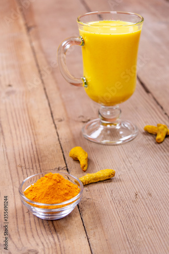 Golden milk in a glass gray cup on a wooden background