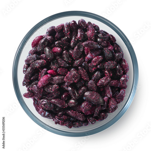 Frozen honeysuckle berries in a glass plate on a white background. Isolated frozen berries. Top view