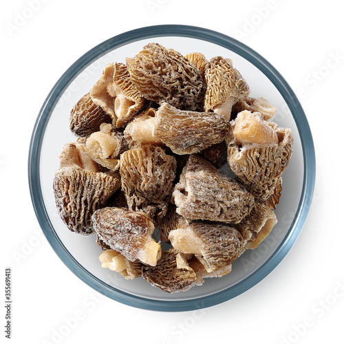 Frozen morel mushrooms in a glass plate on a white background. Isolated frozen mushrooms. Top view. 
