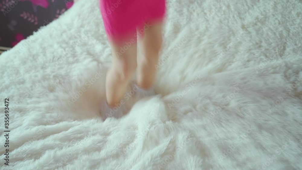 The golden-haired little girl jumps on the bed and faces in the camera The golden-haired little girl jumps on the bed and faces in the camera