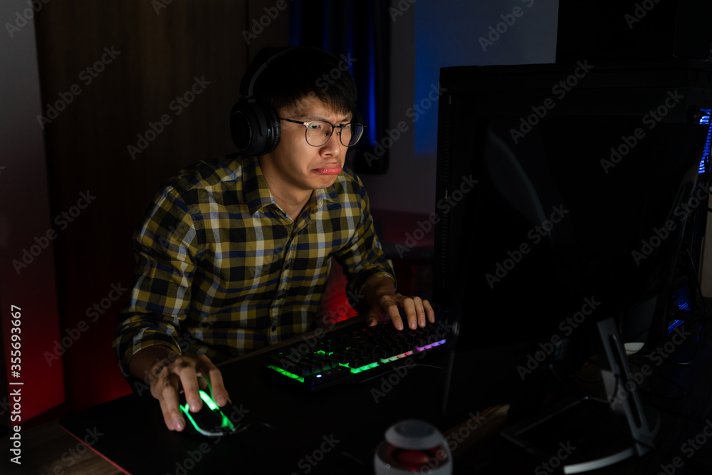 Asian man gamer in headphones stressed with hand feel depressed or angry shocked when losing the video game on computer Fear and upset for mistake, video game technology and e-sport concept Asian man gamer in headphones stressed with hand feel depressed or angry shocked when losing the video game on computer Fear and upset for mistake, video game technology and e-sport concept