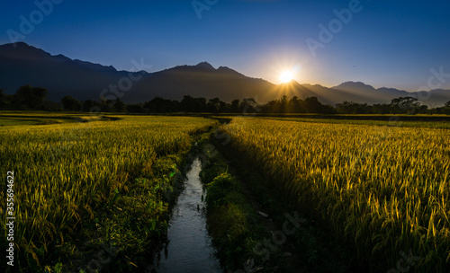 Sun setting behind hills, mountains, canals and paddy fields in a valley in Nepal. View of Rampur, Palpa Nepal. photo