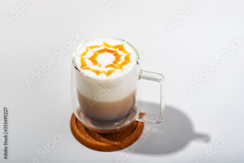 Coffee with Milk froth and caramel in double layer grass on woodplate photo