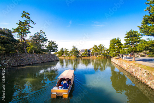 Sightseeing boat sailing on moat around Matsue Castle in Matsue, Shimane Japan. The castle is a national treasure in Japan