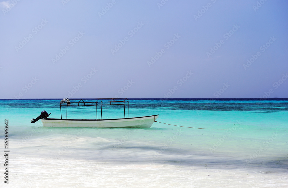 White sandy beach with sea and boat.Tropical seashore scenery. Exotic island vacation