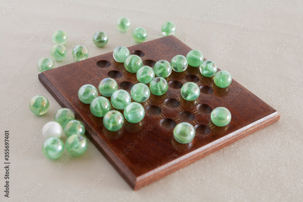 glass marble solitaire game on wooded board glass marble solitaire game on wooded board