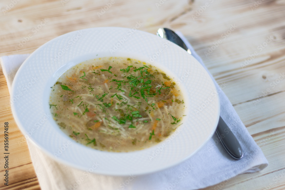 Spaghetty soup lapsha in white plate with spoon on wooden table Spaghetty soup lapsha in white plate with spoon on wooden table