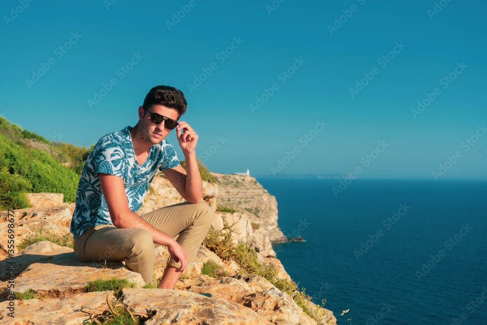 Fototapeta premium Young man sitting at the sea on the horizon