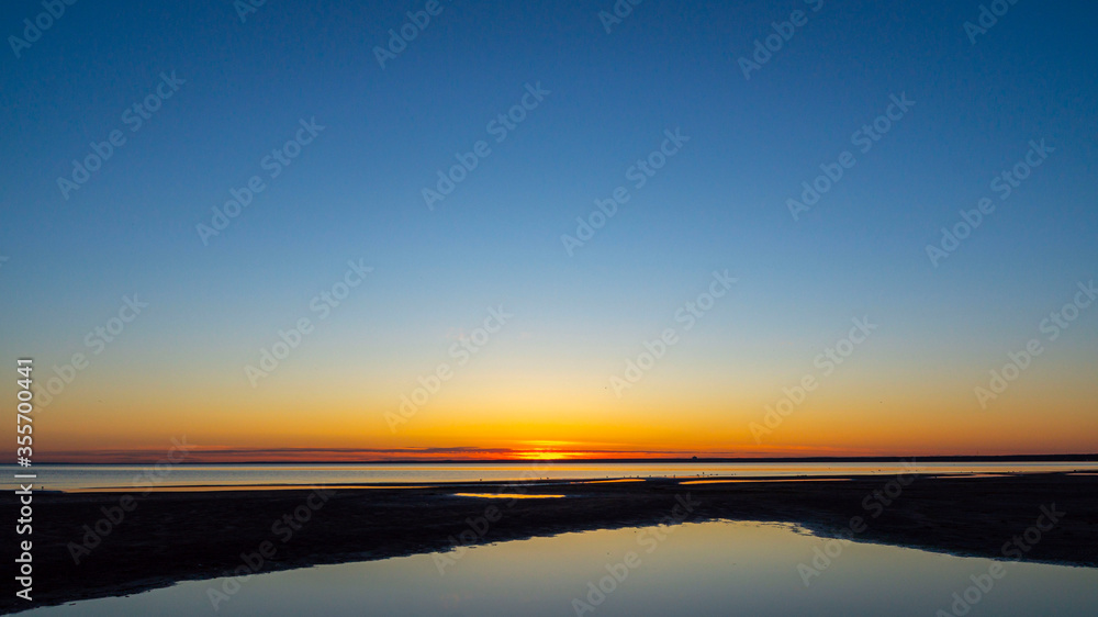 Colorful sunset on the beach. The sky reflected in the water.