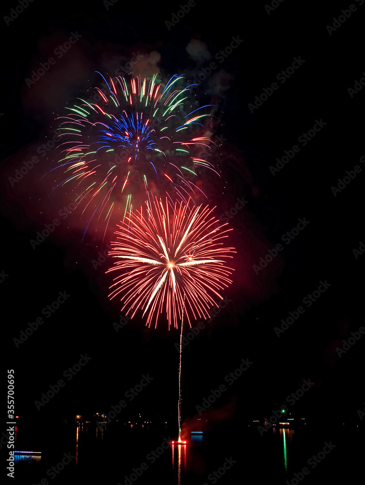 Large 4th of July fireworks being launched from a boat in the middle of a lake at night. Celebration of Independence Day holiday or New Years events. Large 4th of July fireworks being launched from a boat in the middle of a lake at night. Celebration of Independence Day holiday or New Years events.