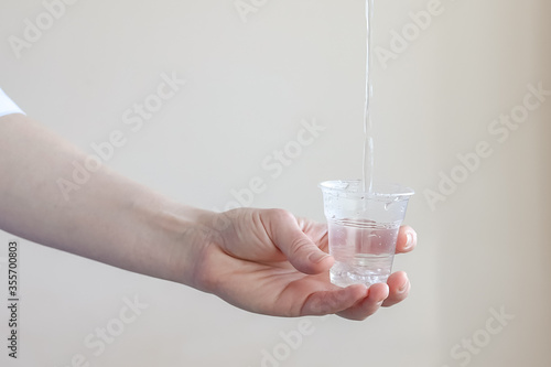 a trickle of water pours into a plastic transparent Cup