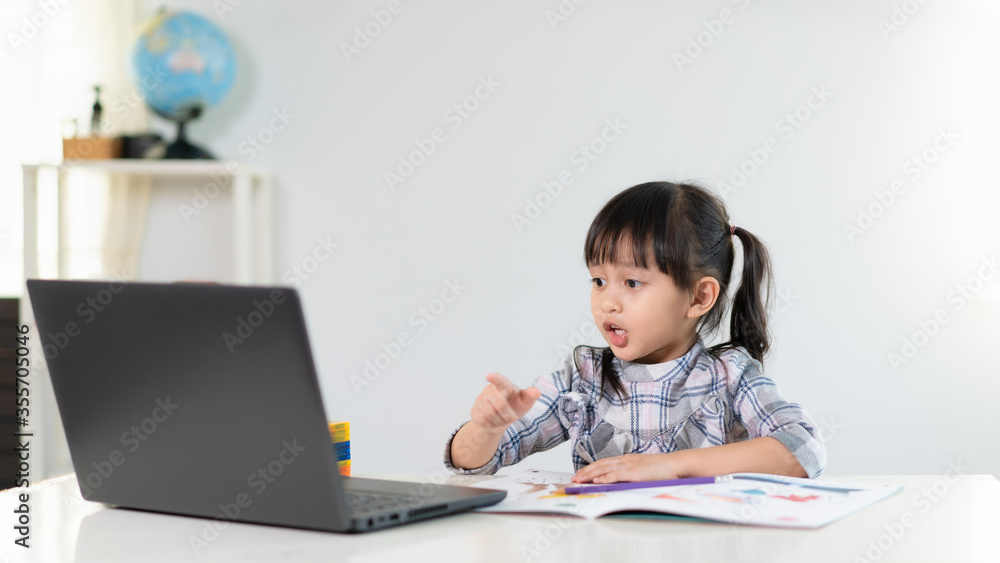 Attractive asian schoolgirl is speaking with teacher and classmate to studying her online lesson at home, social distance during quarantine, self-isolation, online education concept, homeschooling.