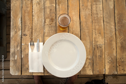 plate, cutlery, glass beer on rustic wooden planes table restaurant