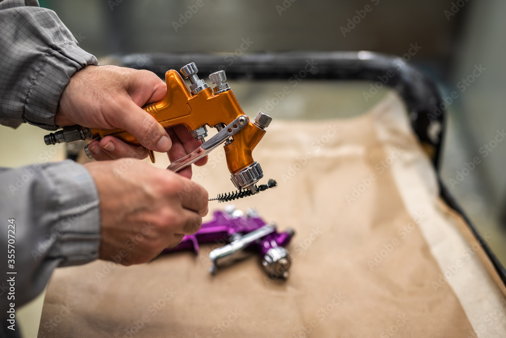 The hands of an employee of the shop painting cleaning spray gun