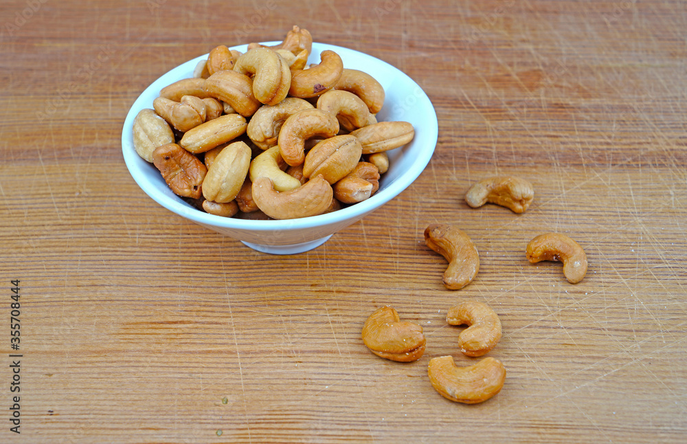 Plateful of Organic cashew and Spilled cashew on Wooden Background Plateful of Organic cashew and Spilled cashew on Wooden Background