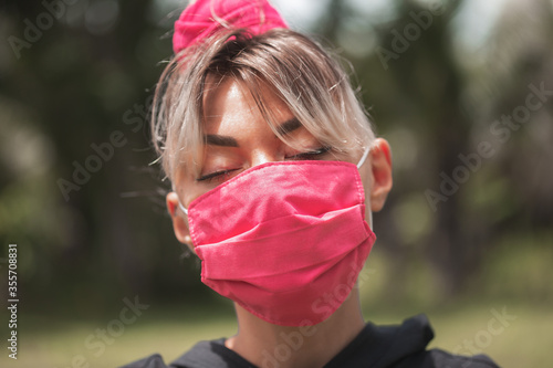 The girl in pink medical mask on nature background closeup