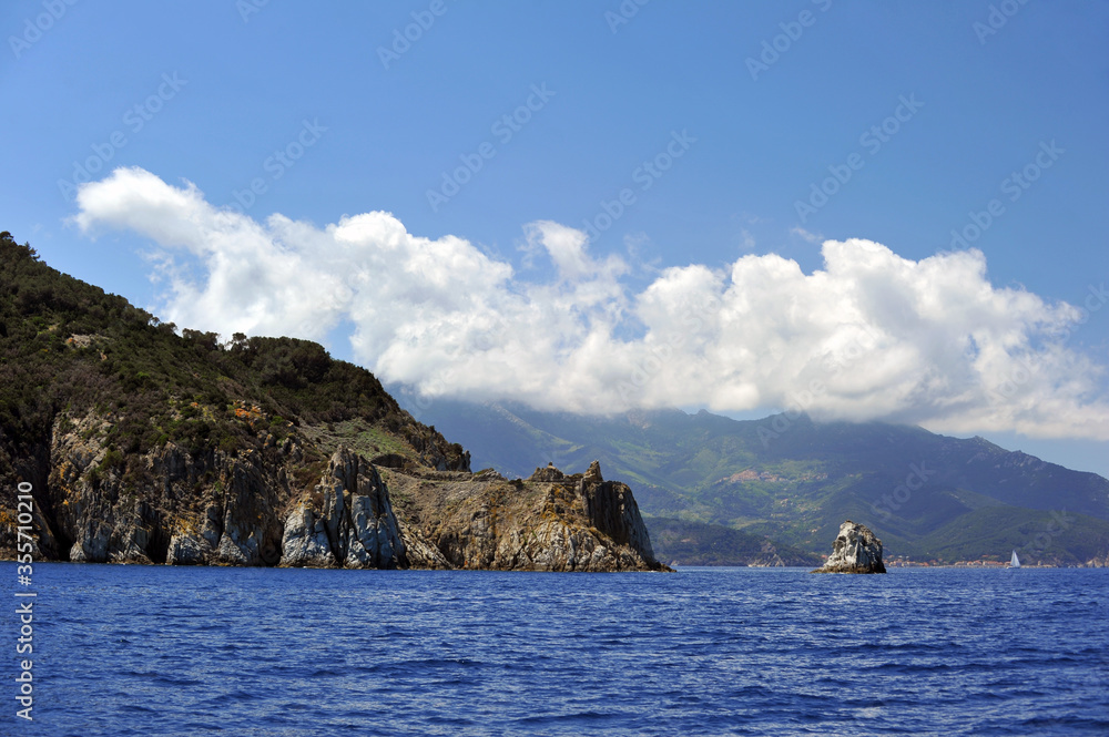 Sailing yacht near the Italian coast with mountains that covered thick vegetation